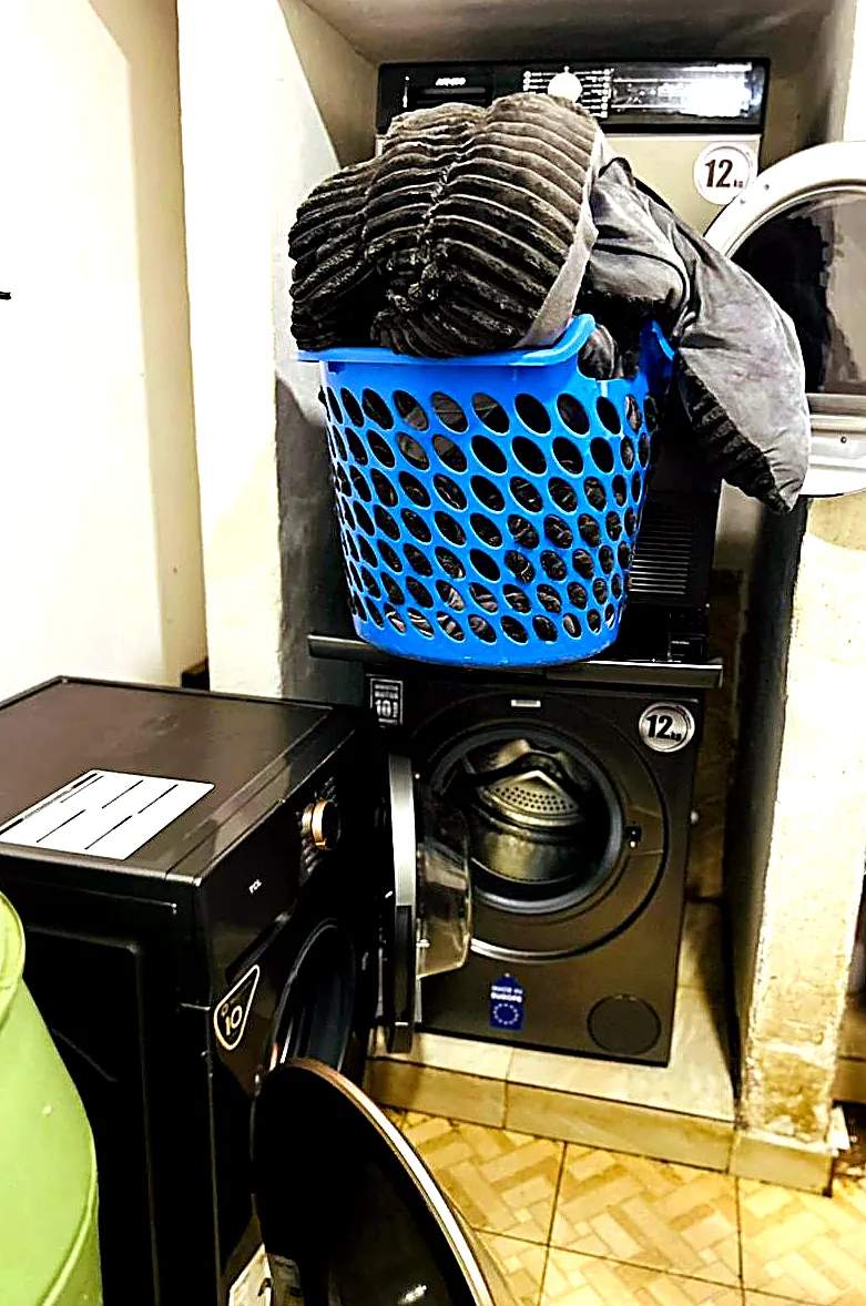 Freshly washed towels and linens in a basket beside the dryer